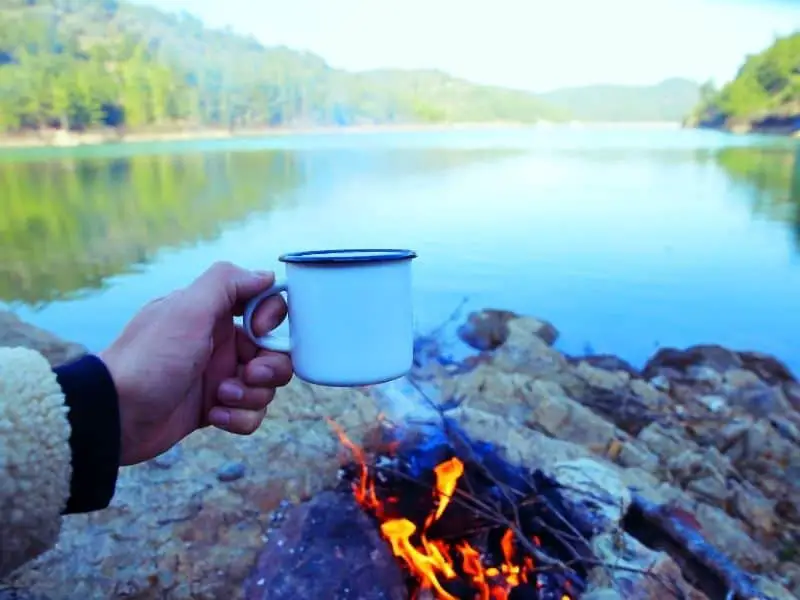 Drinking coffee by the fire while camping